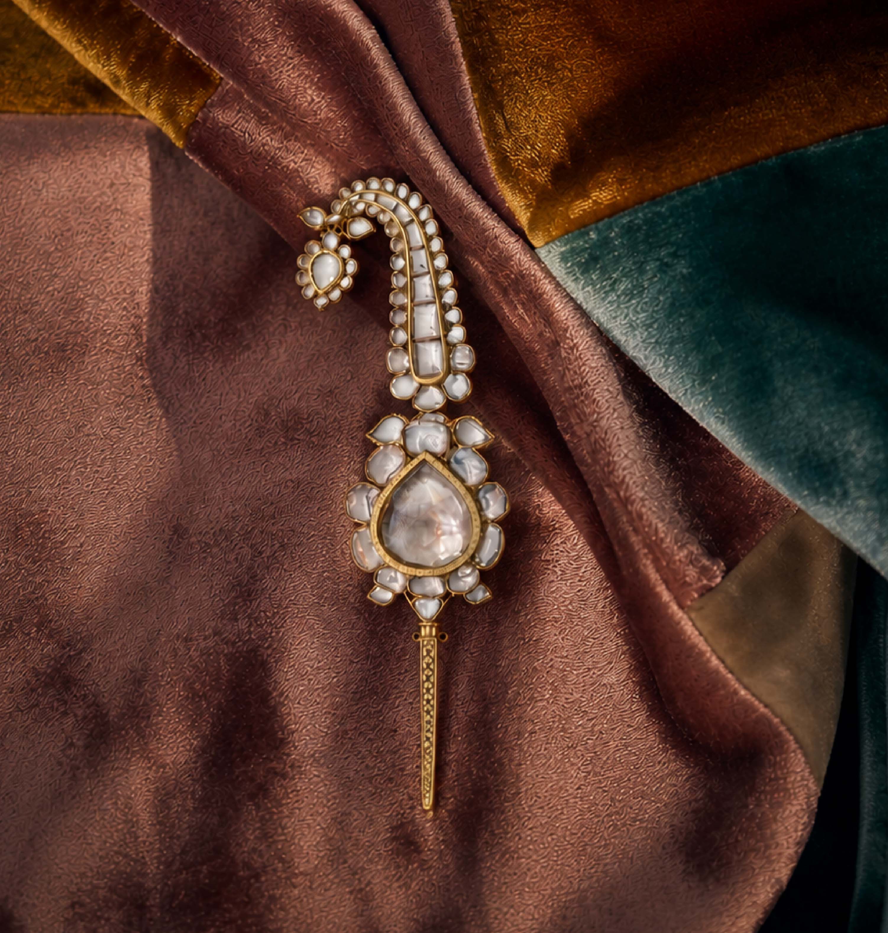 Pearl and polki kalgi with a drop-shaped uncut diamond, resting on velvet