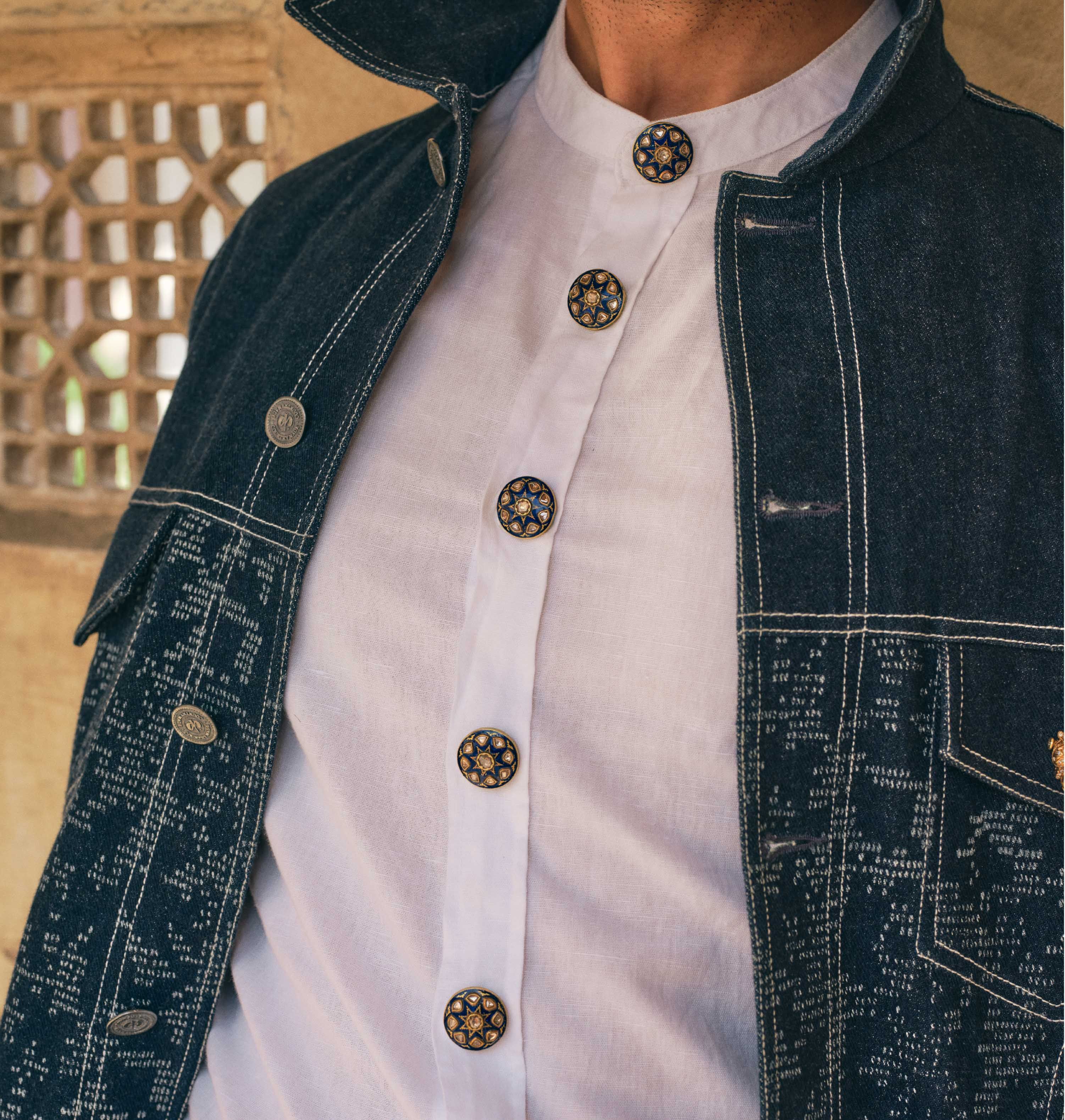 Enamelled gold buttons on a white shirt worn with a denim jacket