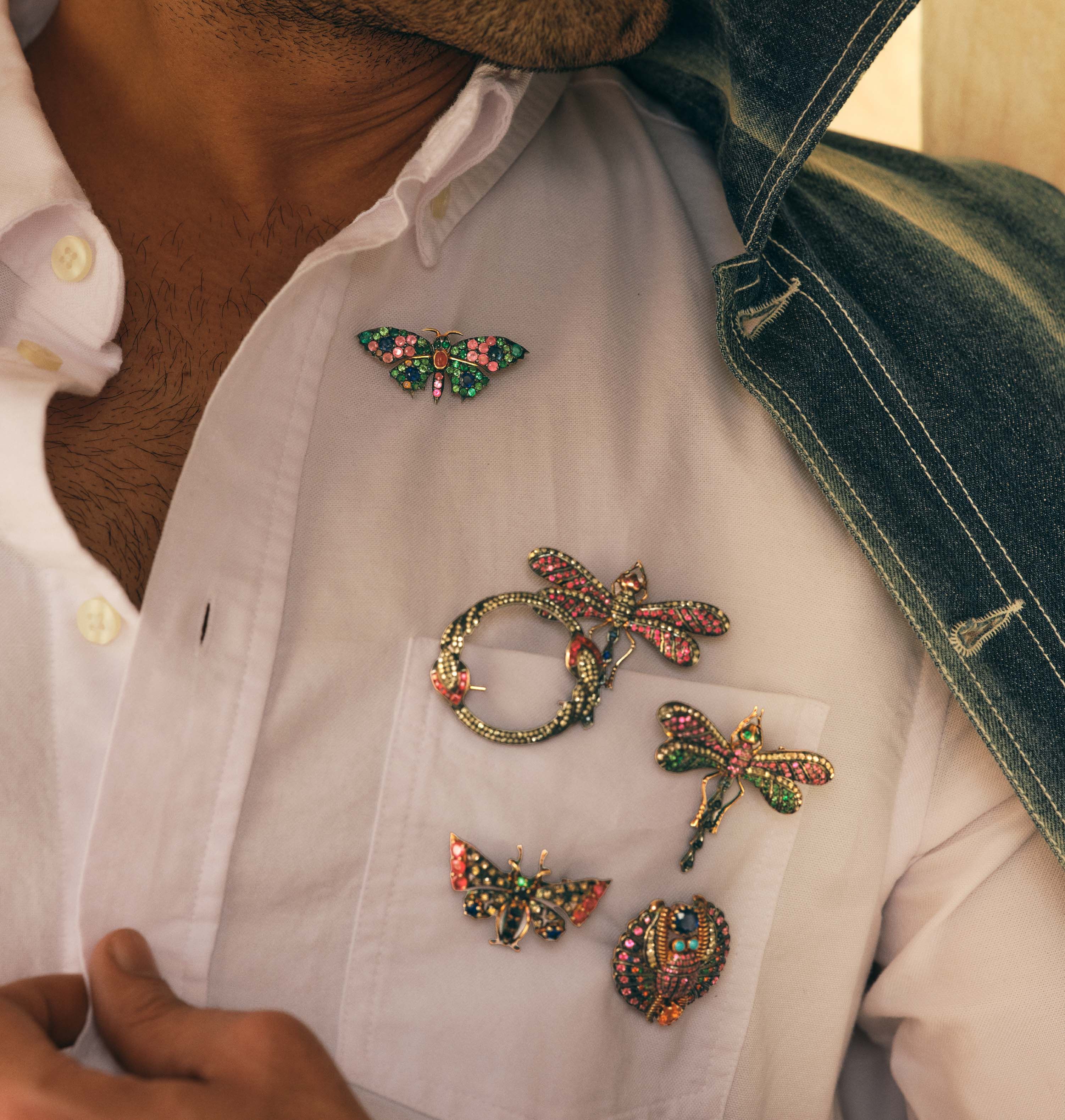 Gem-set insect brooches pinned to a white shirt pocket